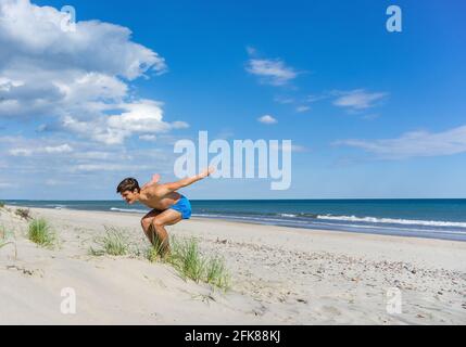 Kaliningrad region, Baltic Sea, Russia, June 6, 2020. A young athlete on the beach. Gymnastics classes at sea. Charging on the beach. Stock Photo