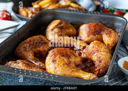 Delicious oven roasted chicken legs with a german tomato curry sauce served in a baking dish on kitchen table background Stock Photo