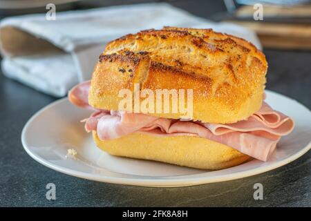 Delicious german bun from a bakery with roasted pepper and salt served with ham on a plate Stock Photo