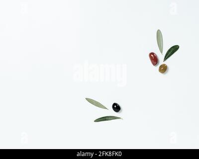 Olives tree leaves and fruits on white background. Top view or flat lay. Olives isolated on white with copy space Stock Photo
