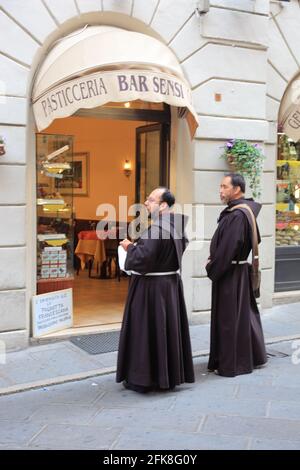 Zwei Moenche stehen vor einer Baeckerei in der Altstadt von Assisi, Umbrien, Italien Stock Photo