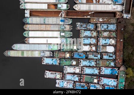 Lots of abandoned transport barges moored side by side at the wharf. River transport industry. Stock Photo