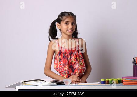 Indian Asian Girl enjoying Painting at home with paper, water colour and art brush. Stock Photo