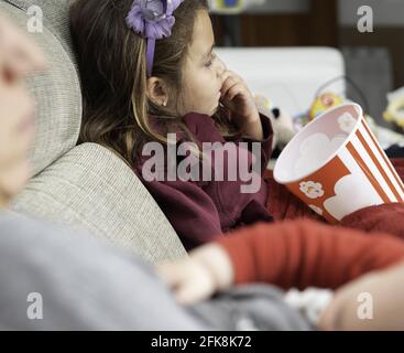 Latina girl eating popcorn and watching a movie with light off Stock ...