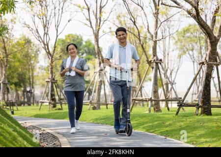 Couple workout and exercise with scooter together outdoor in park Stock Photo