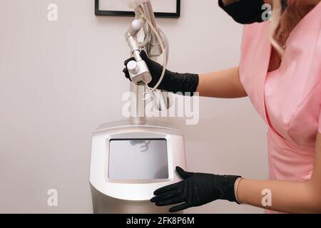 Beautician woman holding in black gloves. Beauty device laser CO2 fractional. Concept of rejuvenation and anti-aging procedures in beauty salon. Stock Photo