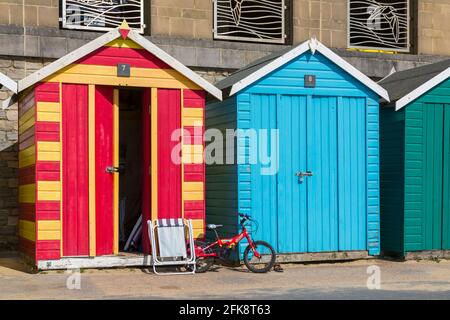 Childs bike bicycle and folded chair leant against colourful beach huts at Boscombe, Bournemouth, Dorset UK in April