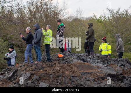 People look on as a 26-foot-long Buffalo tank is extracted from the earth in Crowland, Lincolnshire, where it has been buried for 74 years since it was brought into the village to help during heavy floods in March 1947. Sixteen of the amphibious Buffalo tanks were used to help seal the breach when a combination of heavy snow, high tides, rain and wind caused the River Welland to break its banks. Picture date: Thursday April 29, 2021. Stock Photo