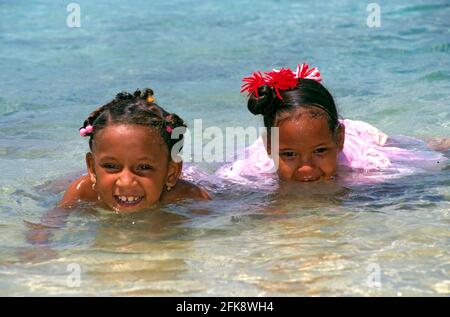 Dominikanische Republik, badende einheimische Kinder am Strand bei Puerto Plata. Im Haar tragen sie traditonellen einheimischen Kinder-Schmuck. Stock Photo