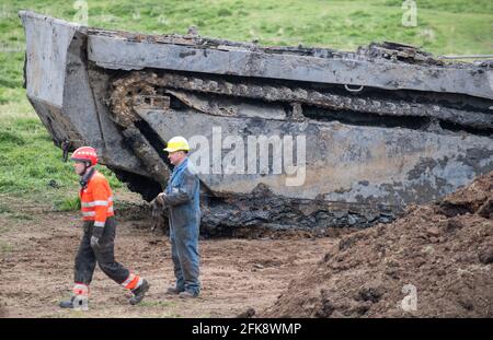 A 26-foot-long Buffalo tank is extracted from the earth in Crowland, Lincolnshire, where it has been buried for 74 years since it was brought into the village to help during heavy floods in March 1947. Sixteen of the amphibious Buffalo tanks were used to help seal the breach when a combination of heavy snow, high tides, rain and wind caused the River Welland to break its banks. Picture date: Thursday April 29, 2021. Stock Photo