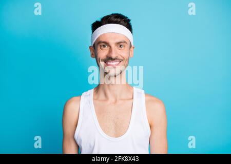 Portrait of positive sportive man look in camera wear white sport undershirt isolated over blue color background Stock Photo