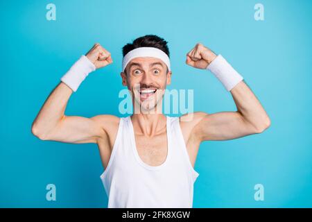 Photo of surprised sportive man show triceps muscles after gym result wear white tank-top singlet isolated over blue color background Stock Photo