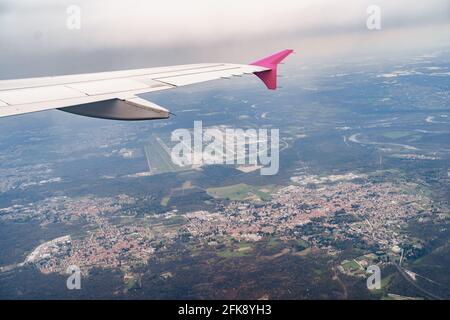 View from the window of a flying plane on the city, roads, green forest, fields Stock Photo