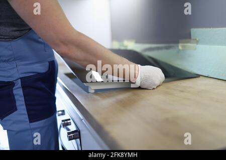 Master installs electric hob on kitchen cabinet Stock Photo