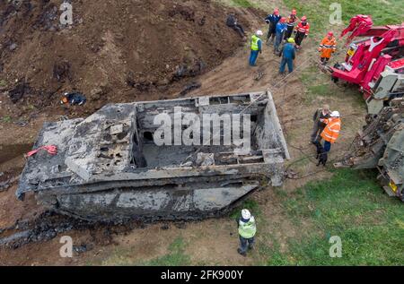 A 26-foot-long Buffalo tank is extracted from the earth in Crowland, Lincolnshire, where it has been buried for 74 years since it was brought into the village to help during heavy floods in March 1947. Sixteen of the amphibious Buffalo tanks were used to help seal the breach when a combination of heavy snow, high tides, rain and wind caused the River Welland to break its banks. Picture date: Thursday April 29, 2021. Stock Photo