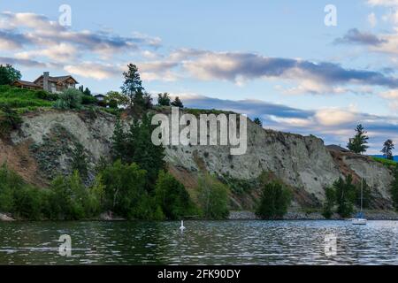 PENTICTON, CANADA - JULY 04, 2020: lake landscape with sailboats calm morning and house on the cliff. Stock Photo