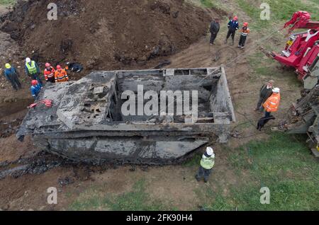 A 26-foot-long Buffalo tank is extracted from the earth in Crowland, Lincolnshire, where it has been buried for 74 years since it was brought into the village to help during heavy floods in March 1947. Sixteen of the amphibious Buffalo tanks were used to help seal the breach when a combination of heavy snow, high tides, rain and wind caused the River Welland to break its banks. Picture date: Thursday April 29, 2021. Stock Photo