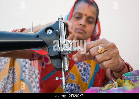 PORTRAIT OF A RURAL WOMAN using sewing machine Stock Photo