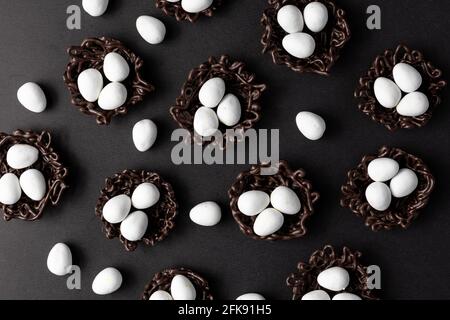 small Easter eggs in chocolate nests on a black background decoration. Stock Photo