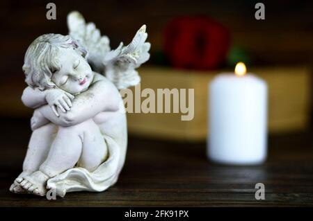 Angel, white candle and red rose on wooden background Stock Photo