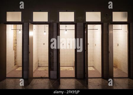 Row of showers in an abandoned old building with formulas written on the tiled walls. Stock Photo
