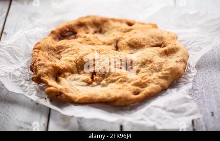 Delicious traditional hungarian baked and fried langos served on a paper. Stock Photo