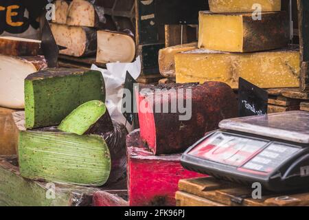 Variety of colorful cheese at a market stand, naturally colored by tomatoes and pesto Stock Photo