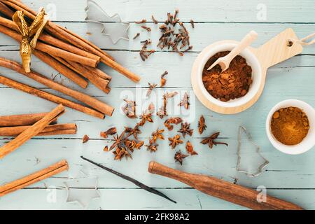 Baking spices like cinnamon, star anise and cocoa on clear blue wooden table, decorated with christmas cookie cutters. Top view. Stock Photo