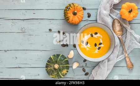 Bowl with pumpkin soup on light blue rustic wooden background and pumpkins as decoration. Top view with copy space Stock Photo