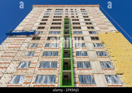 Construction suspended cradle. Construction cradle with workers on the facade of the building. Insulation of building walls with insulation. Stock Photo