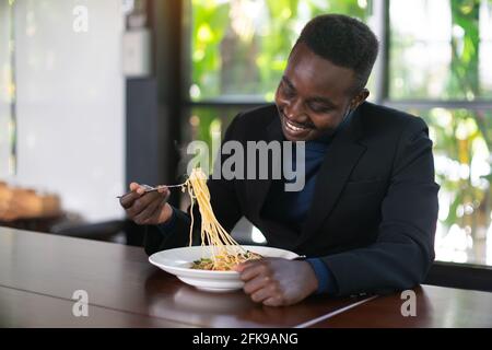 African businessman having a happy lunch with eating Spaghetti in restaurant Stock Photo