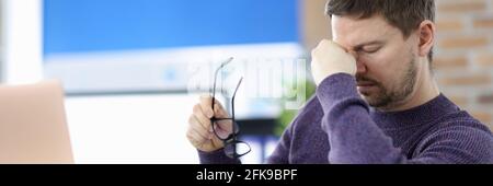 Man siting at table in office and holding bridge of his nose Stock Photo