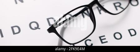 Glasses for vision in black frames lying on test chart closeup Stock Photo