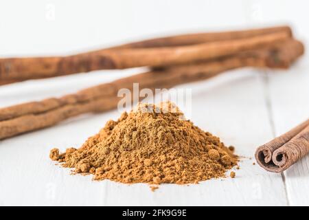 Close-up of cinnamon powder and cinnamon sticks on white wood Stock Photo