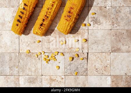 Delicious organic homemade hot grilled corn cobs on earth toned tales background top view Stock Photo