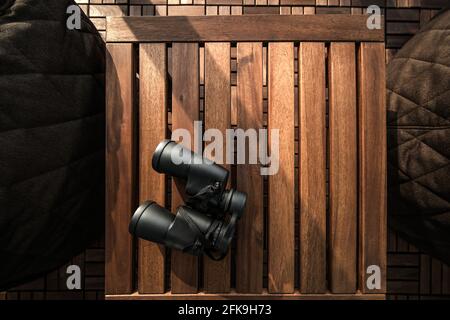 Black binoculars on a brown wooden table background with copy space Stock Photo