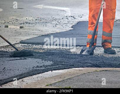 Worker in an orange uniform during a road repair Stock Photo