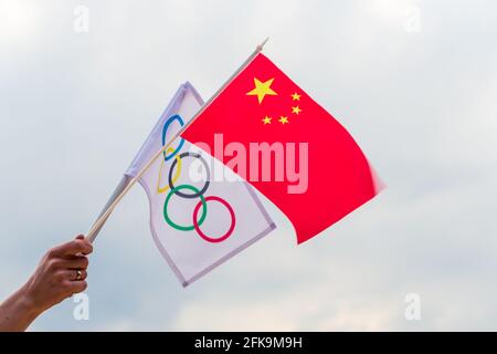 Fan waving the national flag of  China and the Olympic flag with symbol olympics rings. Stock Photo