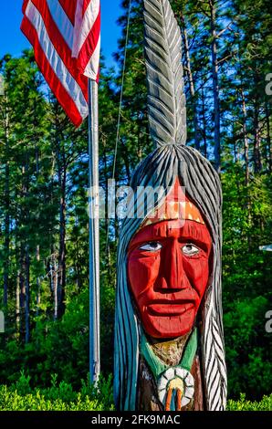 A wooden Indian stands with an American flag at the entrance to Indian Point RV Resort, April 25, 2021, in Gautier, Mississippi. Stock Photo