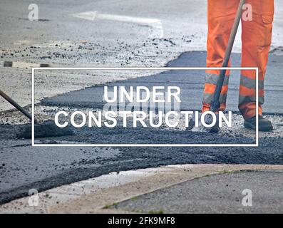 Text "Under construction" with workers as background. Stock Photo