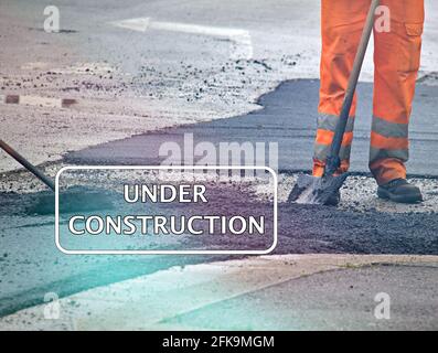 Worker in an orange uniform during a road repair with the text "under construction" Stock Photo