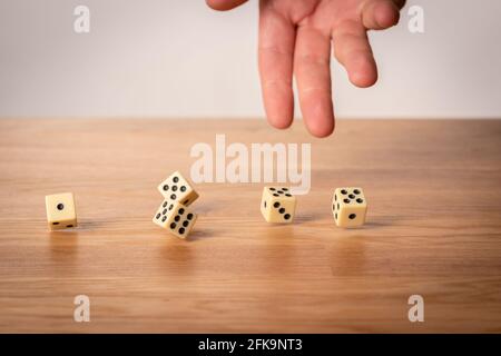 Hand throwing five dice on a wooden table. Stock Photo