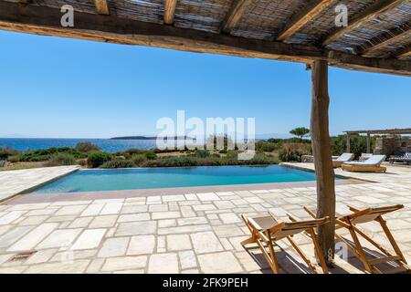 cozy sun loungers on the mediterranean garden terrace with swimming pool near sea. Stock Photo