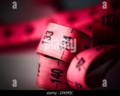 Close up tailor measuring tape on white table background. White measuring tape shallow depth of field. Macro. Stock Photo
