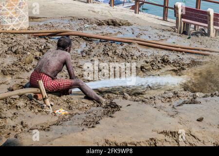 VARANASI, INDIA - OCTOBER 25, 2016: Local man cleans mud sediments at Ghats riverfront steps left after monsoon period flooding in Varanasi, India Stock Photo
