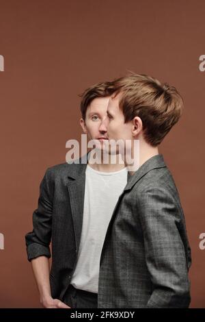 Profile of young man in checkered jacket standing against twin brother, double composition Stock Photo