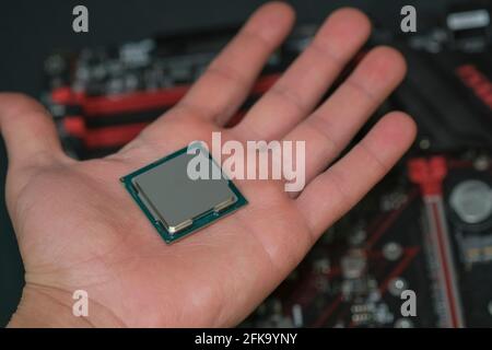 Man hand hold desktop pc cpu processor over hi tech motherboard,computer components chip Stock Photo