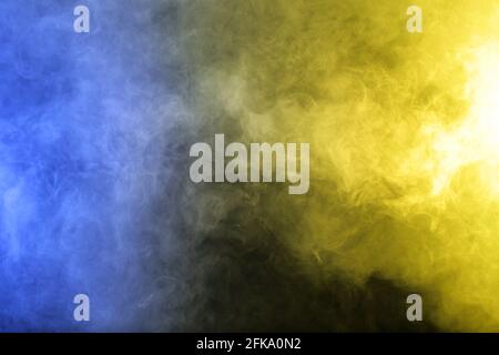 Smoke in blue yellow light on black background Stock Photo