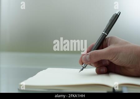 Fountain pen in man's hand writes something in a diary Stock Photo