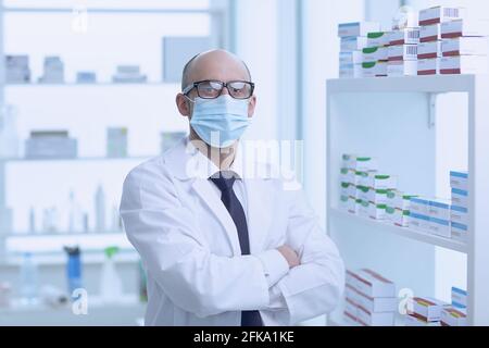 Pharmacist is Working in protective mask. Man Wearing Special Medical Uniform. Located in Pharmacy. Stock Photo